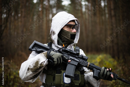Man in a winter camo suit looking with gun ready.