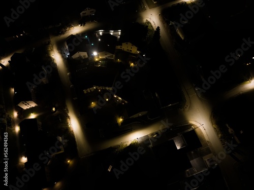 Aerial view of road in rural village at night. Lights illuminating street.
