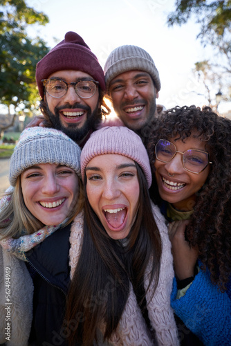 Multiethnic group of people taking selfie outdoors looking at camera cheerfully.