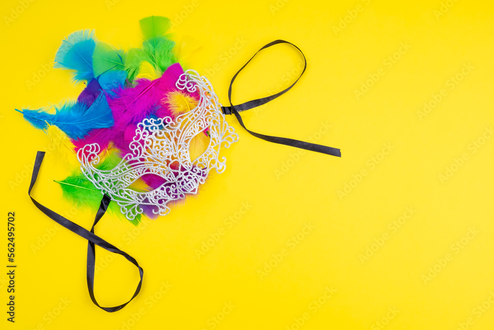 Lacy carnival masks with colored feathers on a yellow background - obrazy, fototapety, plakaty 