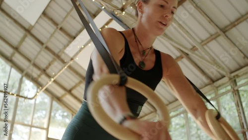 Fit focus woman hanging from suspension ropes during a workout session in a studio