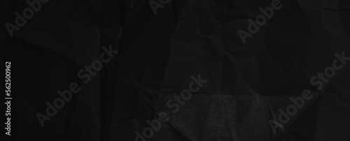 Black background of crumpled paper in the dark. Wide panoramic black background with space for design. Web banner, website header