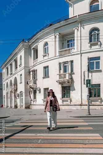 Wallpaper Mural Woman city road crossing. Stylish woman in a hat crosses the road at a pedestrian crossing in the city. Dressed in white trousers and a jacket with a bag in her hands. Torontodigital.ca