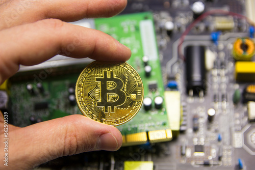 Man's hand holds bitcoin cryptocurrency against the background of a microcircuit