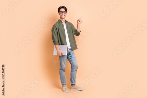 Full length size cadre of young cheerful positive man remote education direct finger point mockup with laptop isolated on beige color background
