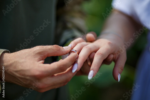 A guy in a military uniform puts on a wedding ring for his beloved close-up © Svitlana