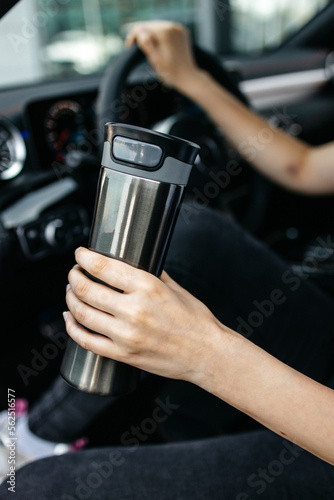 thermo mug thermos in the hands of a woman in the car