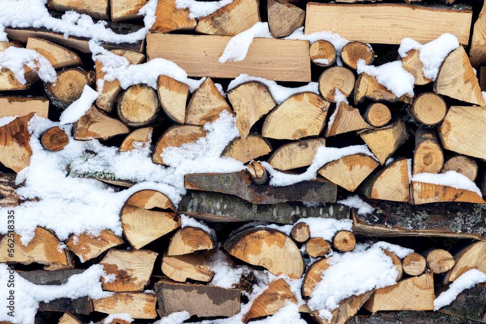 Firewood on pile covered with snow, preparation for the winter season Firewood on pile covered with snow, preparation for the winter season