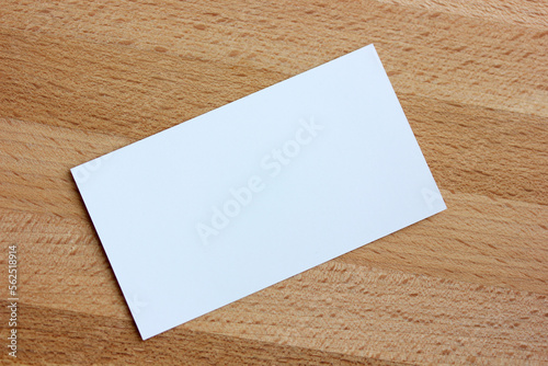 an empty paper business card on a wooden background, top view.