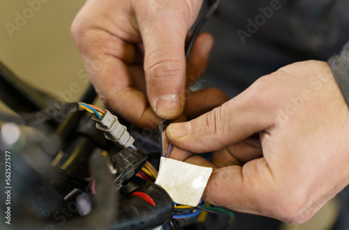 The mechanic sorts out chips for connecting electrical equipment in a motorcycle