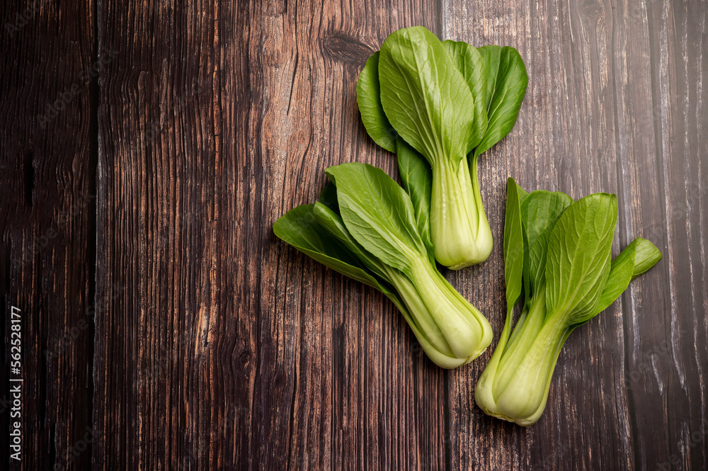 Celery cabbage or peach choi, asian baby salad leaves on wooden background, copy space
