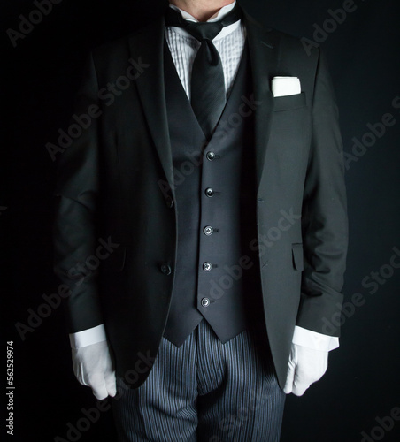 Portrait of Butler in Dark Suit and White Gloves Standing at Attention. Service Industry and Professional Hospitality.