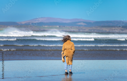 A woman walks along Rossnowlagh beach, one of Ireland's and Europe's best Blue Flag surfing beaches, on the windy shore of Atlantic Ocean  in the south of County Donegal, Ireland photo