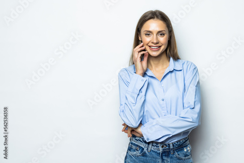 Smiling young business woman with folded hands against white background.