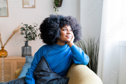 Cheerful black woman sitting on couch