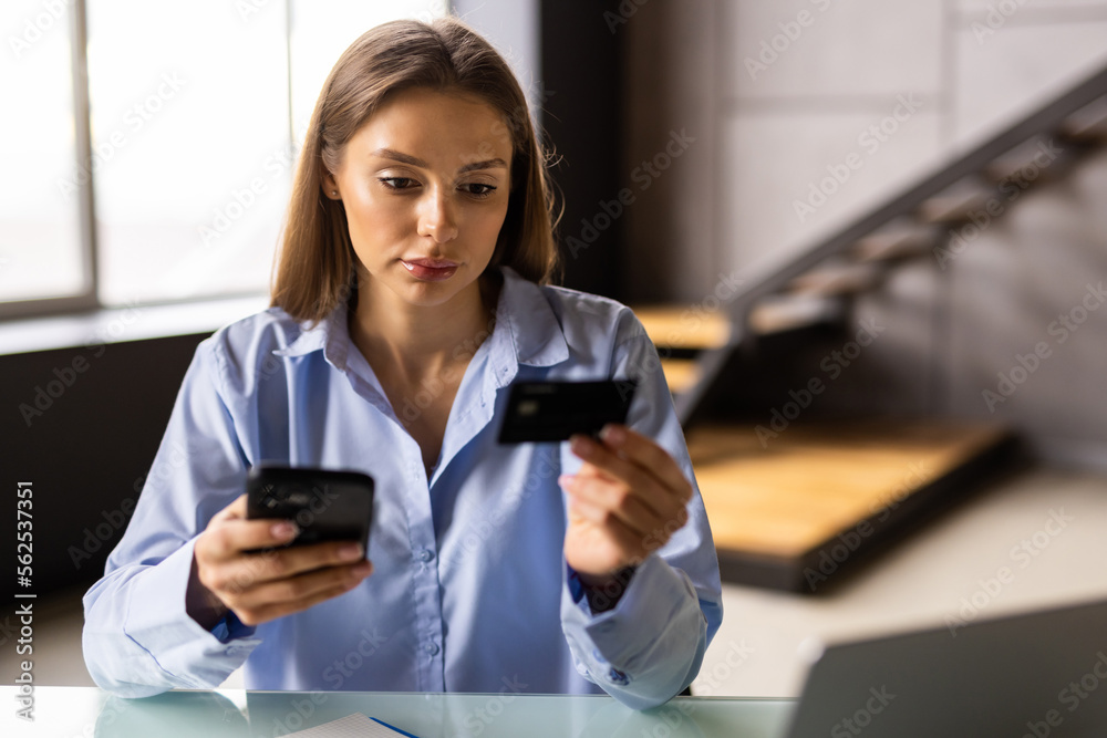 Young woman is doing online purchases. Girl is doing shopping using phone and credit card at home.
