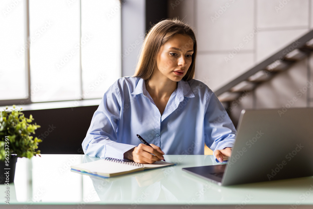 Attractive mature businesswoman working on laptop in her workstation. Attractive mature businesswoman working on laptop in her workstation.