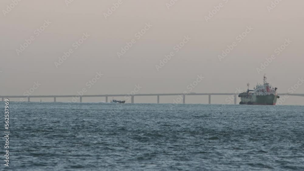 An industrial marine vessel sails the river and the motor boat is floating nearby An industrial marine vessel sails the river and the motor boat is floating nearby