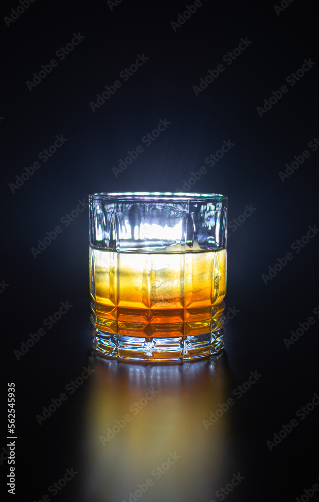 glass with orange yellow liquor on a black background reflection of the glass on the table
glass with orange yellow liquor on a black background reflection of the glass on the table