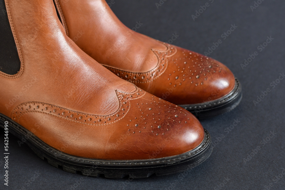Close up view light tan chelsea men boots on dark grey background