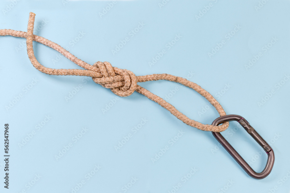 Carabiner in rope knot аigure-eight loop on blue background