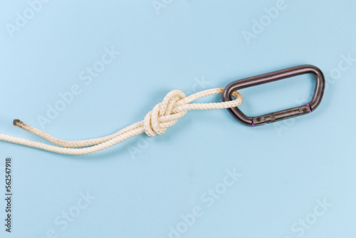 Carabiner in rope knot аigure-eight loop on blue background