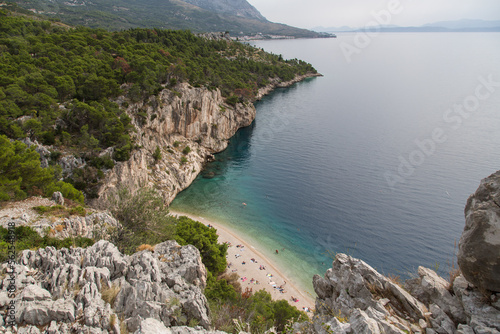 Scenic Nugal Beach-pebbly beach preferred by nudists-below a huge vertical rock wall towering above turquoise water at Gradac viewpoint with a stunning view to the coastline and Mount Biokovo, Croatia © blickwinkel2511