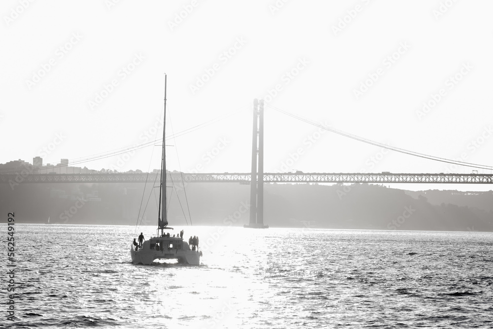 People standing on a sailing yacht sailing along the river towards the bridge