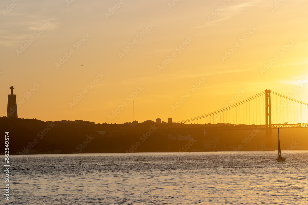 Orange sunset over the Tagus River - the statue of Jesus christ and the bridge over the river