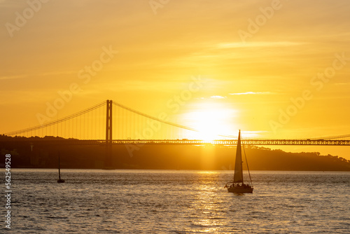 Bright orange sunset over the river and a sailing boat floating