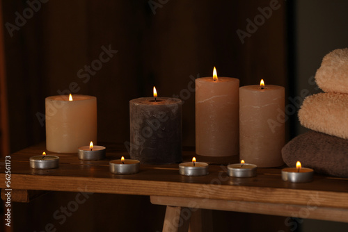 Spa composition with burning candles and towels on wooden table in wellness center