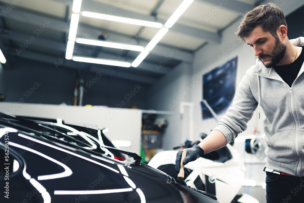 Car expert cleaning the dust of sports car with a car detailing brush. Professionals during work. Garage interior. High quality photo Car expert cleaning the dust of sports car with a car detailing brush. Professionals during work. Garage interior. High quality photo