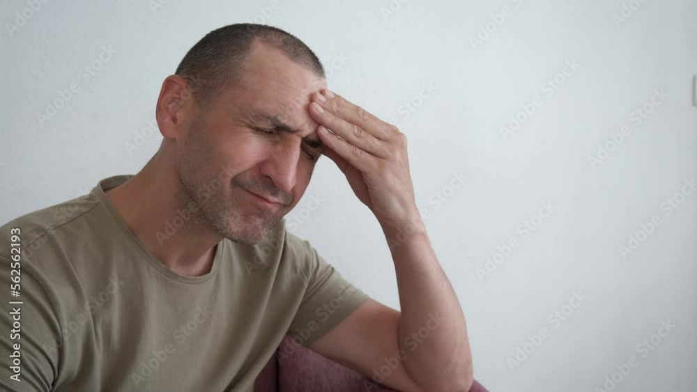 Anxious man experiencing headache. A view of anxious man experiencing head pain on the sofa in loneliness. Anxious man experiencing headache. A view of anxious man experiencing head pain on the sofa in loneliness.