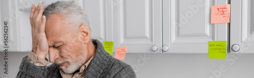 Fotografía stressed man with alzheimer disease touching forehead in kitchen, banner