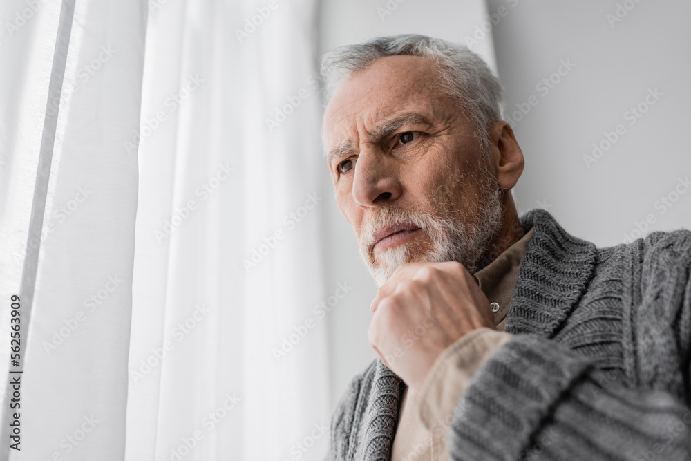 tense man suffering from memory loss caused by alzheimer disease standing with hand near chin at home. tense man suffering from memory loss caused by alzheimer disease standing with hand near chin at home.