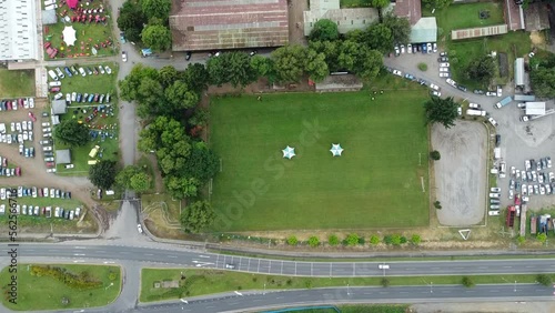 A look at the road, surrounded by a rural fair, where farm products are sold.
Cars drive in and out of town.