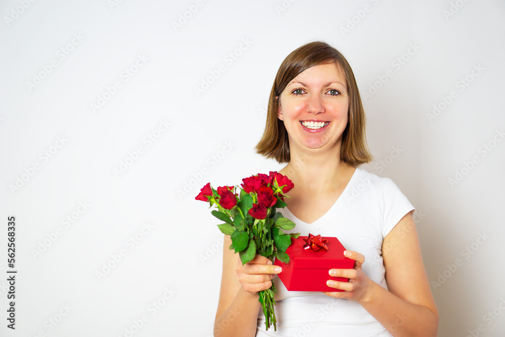 Attractive smiling woman celebrating holiday and holding a gift box and flowers. Attractive smiling woman celebrating holiday and holding a gift box and flowers.