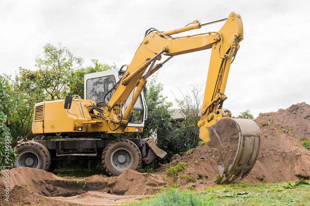 A bucket of excavator with a pile of sand and a ground background. Industrial work on the construction site A bucket of excavator with a pile of sand and a ground background. Industrial work on the construction site