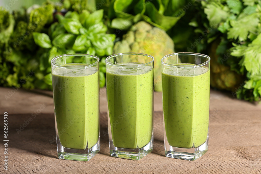 Glasses of fresh green smoothie and ingredients on wooden table Glasses of fresh green smoothie and ingredients on wooden table