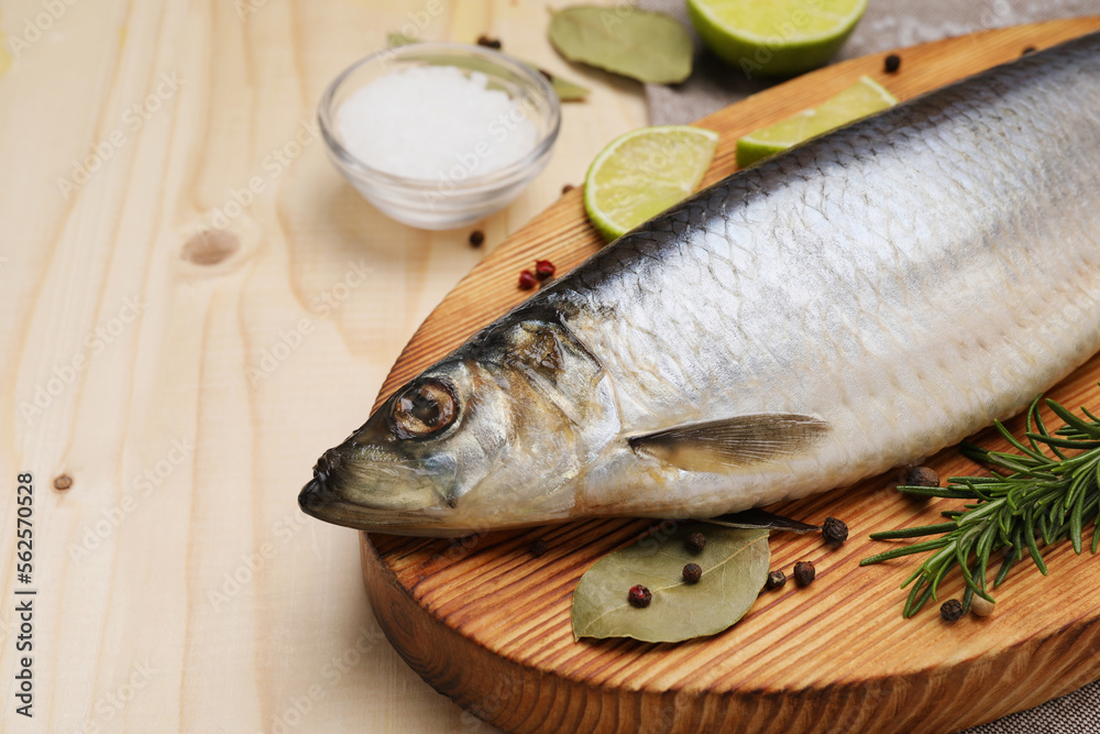Delicious salted herring, bay leaves, lime, rosemary and salt on wooden table, closeup Delicious salted herring, bay leaves, lime, rosemary and salt on wooden table, closeup