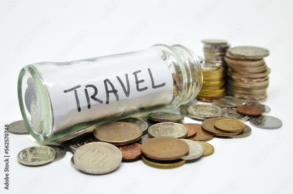 Travel lable in a glass jar with coins spilling out Travel lable in a glass jar with coins spilling out
