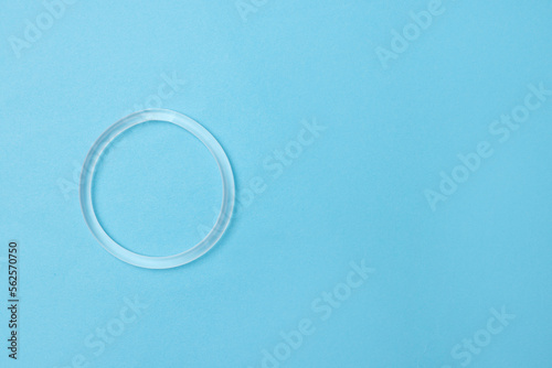 Diaphragm vaginal contraceptive ring on light blue background, top view. Space for text