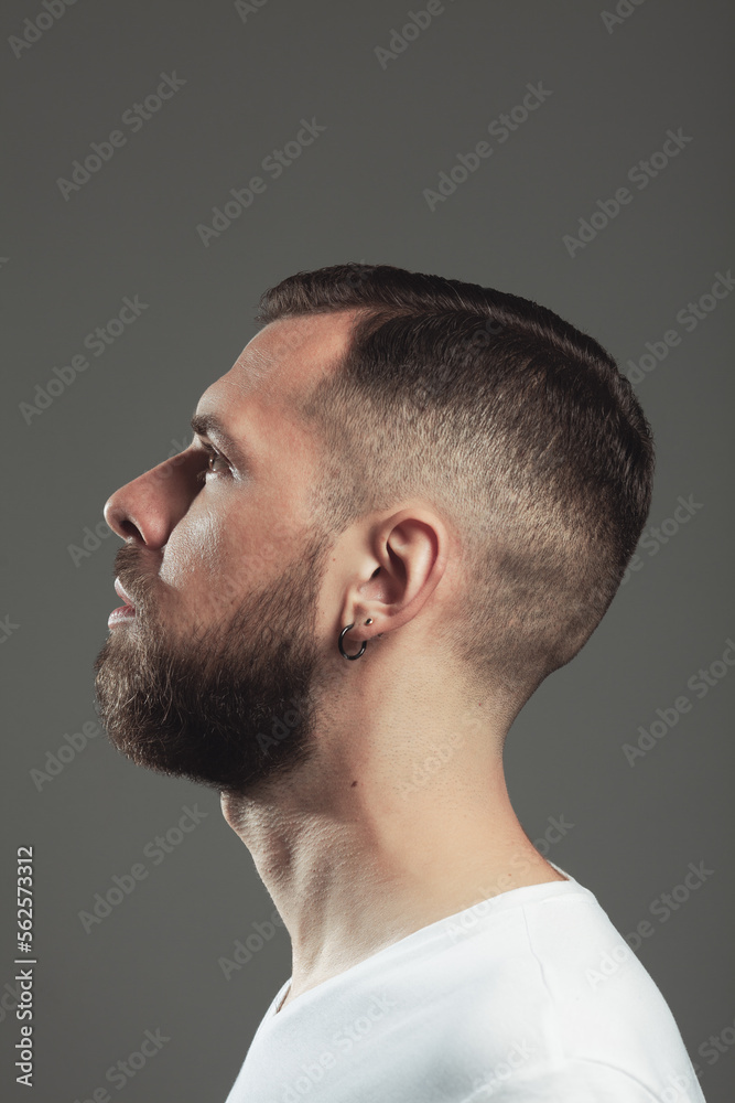 Male beauty concept. Profile portrait of charismatic active 30-year-old man posing over gray background. Perfect haircut. Poster style. Close up. Studio shot Male beauty concept. Profile portrait of charismatic active 30-year-old man posing over gray background. Perfect haircut. Poster style. Close up. Studio shot