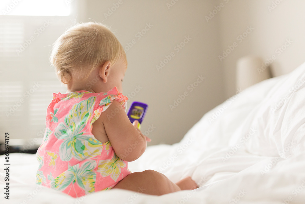 Baby girl playing with toy while sitting on bed at home Baby girl playing with toy while sitting on bed at home