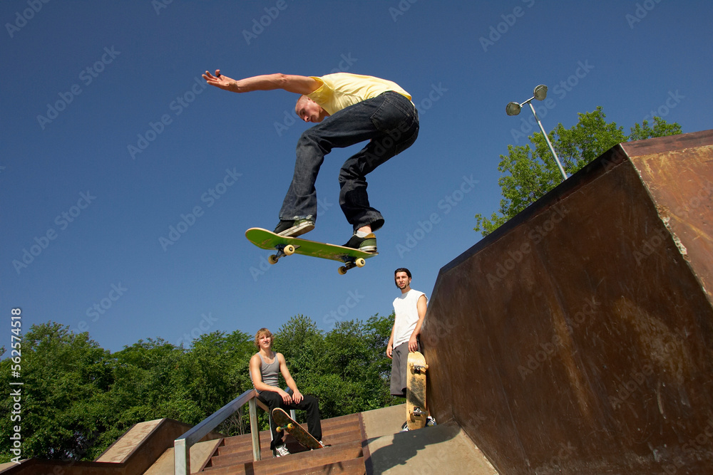 Three skateboarders doing tricks at a skate park.