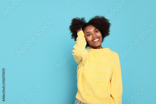 Portrait of smiling African American woman on light blue background. Space for text