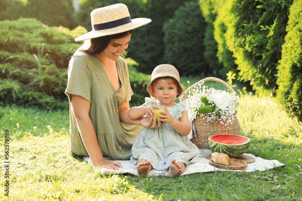 Mother with her baby daughter having picnic in garden on sunny day Mother with her baby daughter having picnic in garden on sunny day