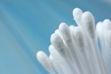 Many cotton buds on light blue background, closeup. Space for text