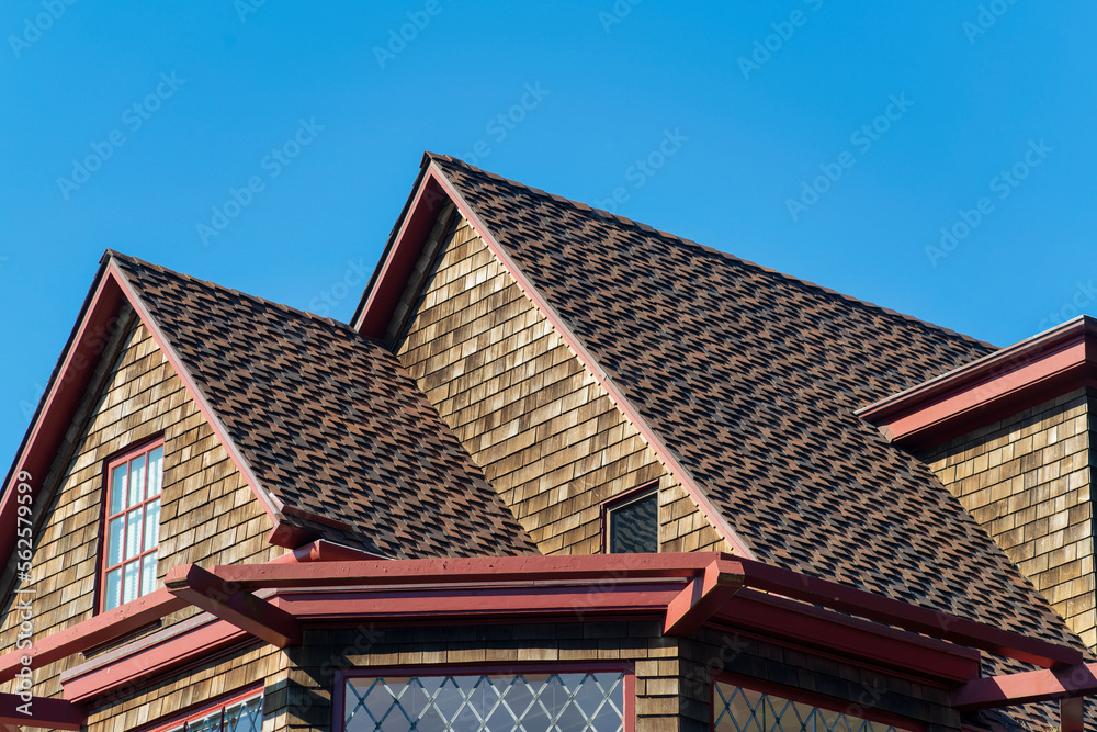 Double gable style roof tops with visible window and dark brown brick with cement roof tiles and gazebo foreground