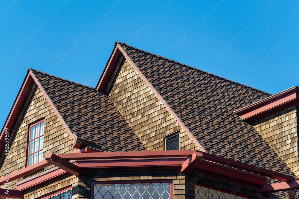Double gable style roof tops with visible window and dark brown brick with cement roof tiles and gazebo foreground Double gable style roof tops with visible window and dark brown brick with cement roof tiles and gazebo foreground